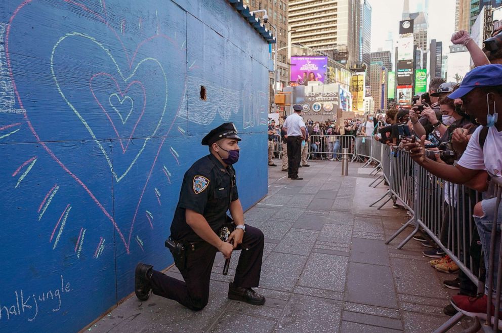 PHOTO: A New York City police officer takes a knee during a demonstration by protesters in Times Square over the death of George Floyd at a rally on May 31, 2020 in New York.