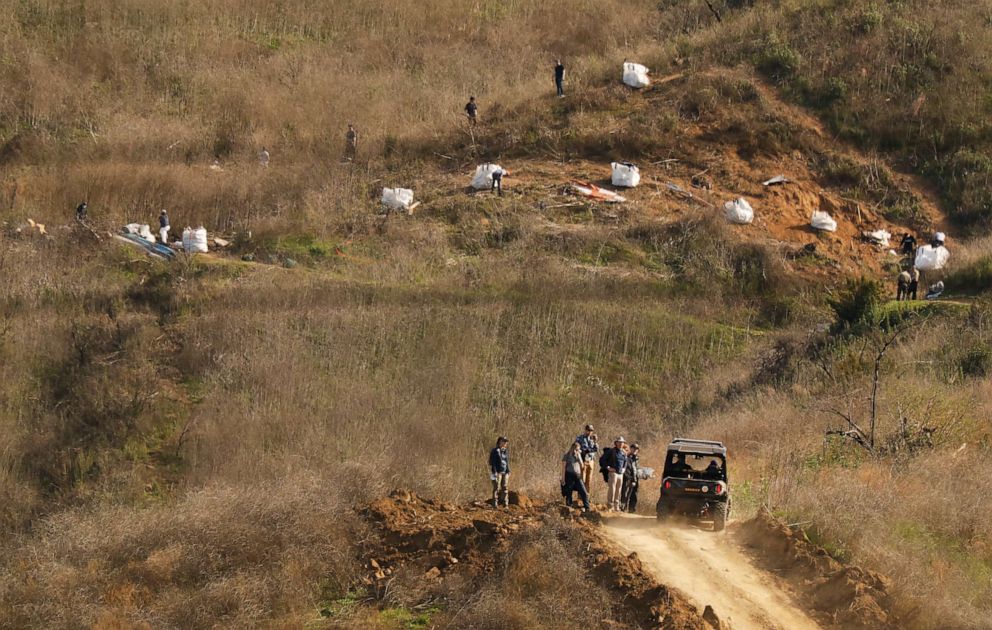 PHOTO: Investigators walk down the bulldozed dirt road Tuesday morning after working at the hillside scene of the helicopter crash that killed Kobe Bryant and eight other people, Jan. 28, 2020 in Calabasas, California.