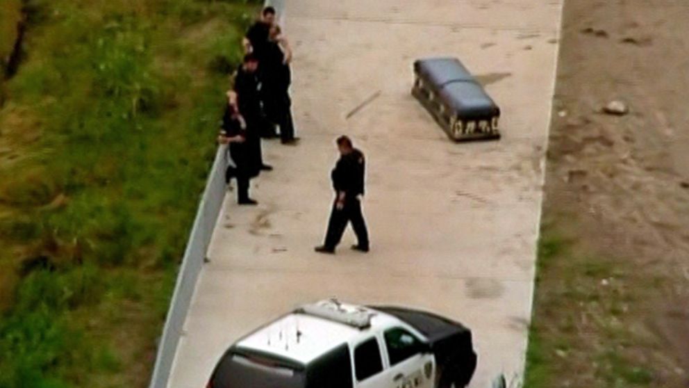 PHOTO: Police stand near a casket that authorities believe was unearthed from the Riceville Cemetery by recent flooding in Houston, Texas on May 26, 2015.