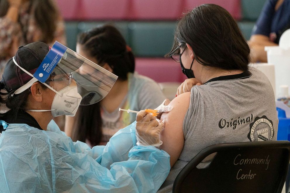 PHOTO: Sisters Guadalupe Flores, 15, right, and Estela Flores, 13, left, from East Los Angeles, get vaccinated with the Pfizer's COVID-19 vaccine at the Esteban E. Torres High School in Los Angeles, Thursday, May 27, 2021. 