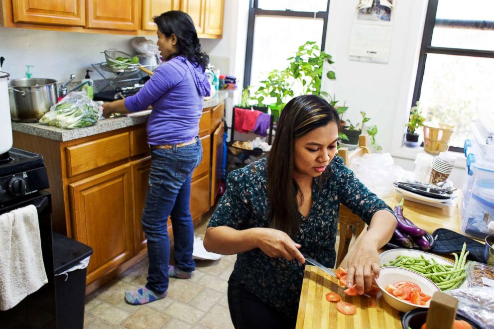 PHOTO: Edith Mendoza, left, and Sherile Pahagas, right, prepare a meal together in the home of Juana Dwyer, Oct. 28, 2017. Mendoza and Pahagas are suing their former employers, a German diplomat and his wife. 
