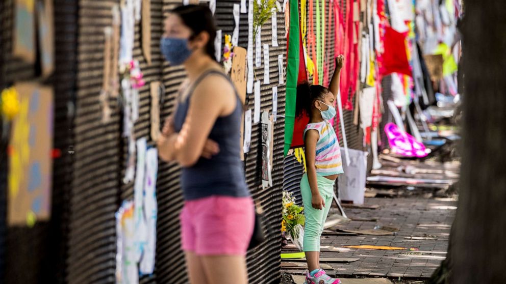 PHOTO: People look at signs on the police fence at in Lafayette Park, June 8, 2020, near the White House in Washington, after days of protest over the death of George Floyd.