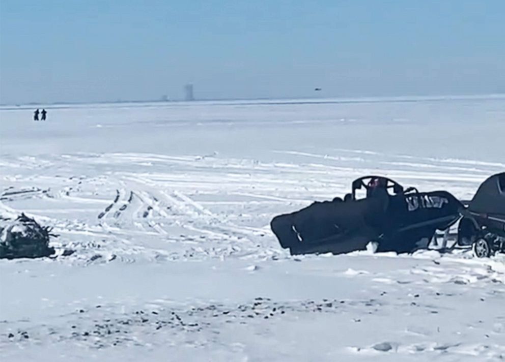 PHOTO: Snowmobiles rest as figures walk in the distance during a rescue operation taking place on ice floes on Lake Erie near Catwaba Island, Ohio, Feb. 6, 2022.