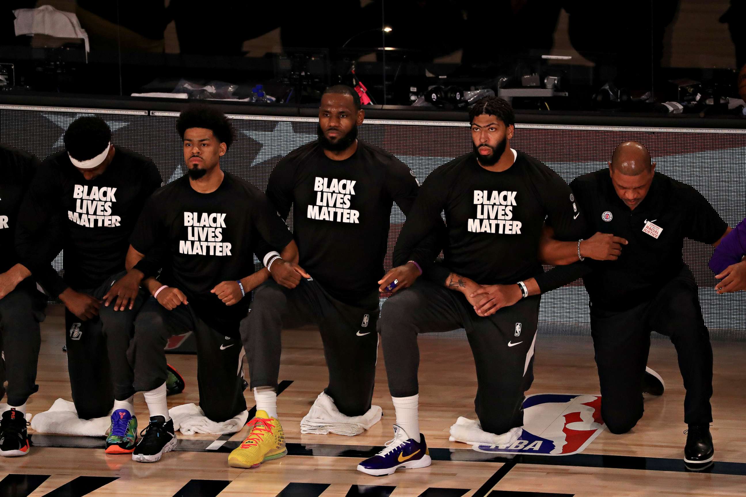 PHOTO: Los Angeles Lakers players, including LeBron James and Anthony Davis, wear Black Lives Matter shirts as they kneel during the national anthem prior to an NBA basketball game against the Los Angeles Clippers, July 30, 2020, in Lake Buena Vista, Fla.