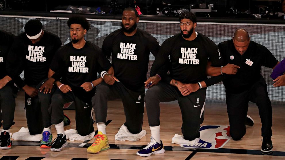 PHOTO: Los Angeles Lakers players, including LeBron James and Anthony Davis, wear Black Lives Matter shirts as they kneel during the national anthem prior to an NBA basketball game against the Los Angeles Clippers, July 30, 2020, in Lake Buena Vista, Fla.
