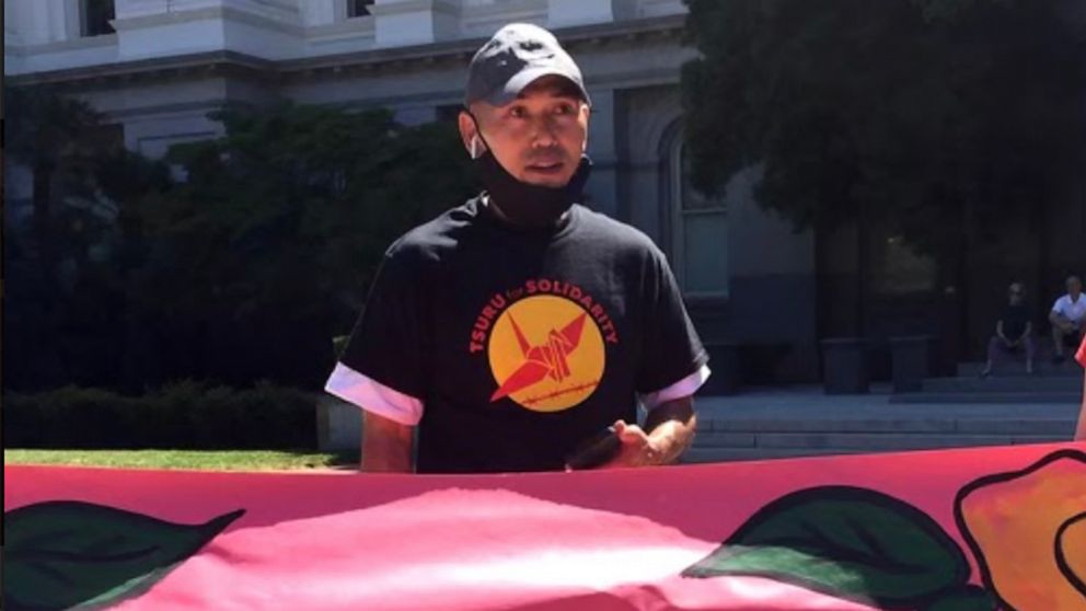 PHOTO: Lam Le stands by a sign at a rally organized by Tsuru for Solidarity on June 4, 2021, in Sacramento, Calif.