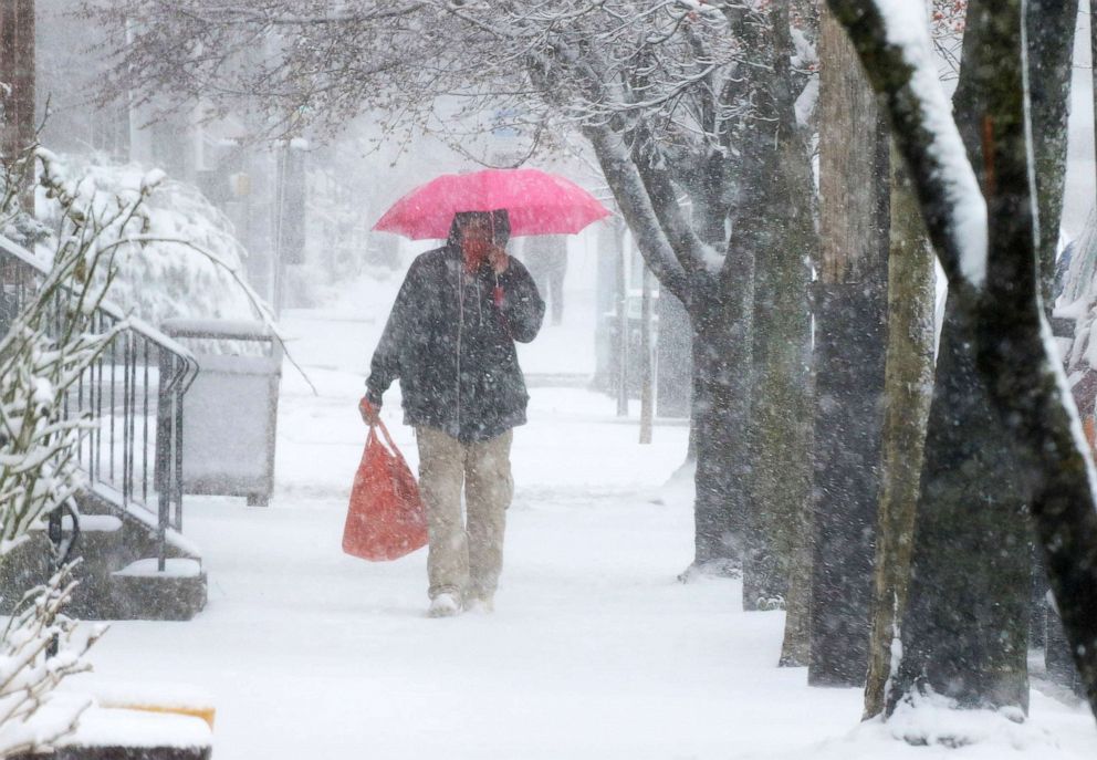 PHOTO: A man carries a shopping bag while walking during a snowstorm in Lancaster City, Pa., March 12, 2022.