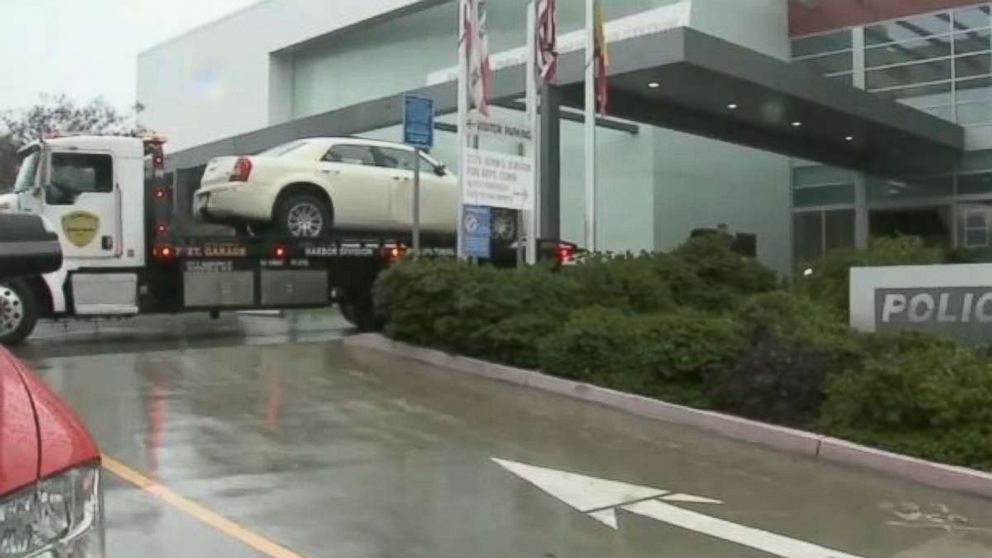 The white sedan of a woman who drove through the front of LAPD's Harbor Area station early Saturday, Feb. 9, 2019, is removed from the scene.