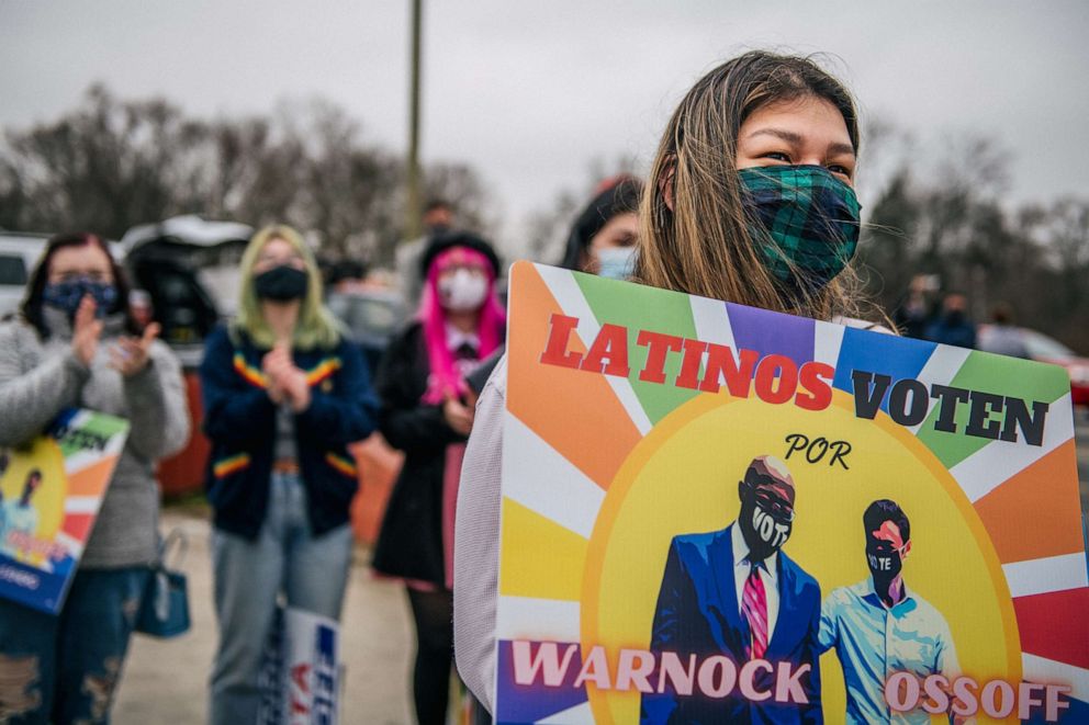 PHOTO: A woman holds a sign during a Latino meet and greet and literature distribution rally, Dec. 30, 2020, in Marietta, Ga. 