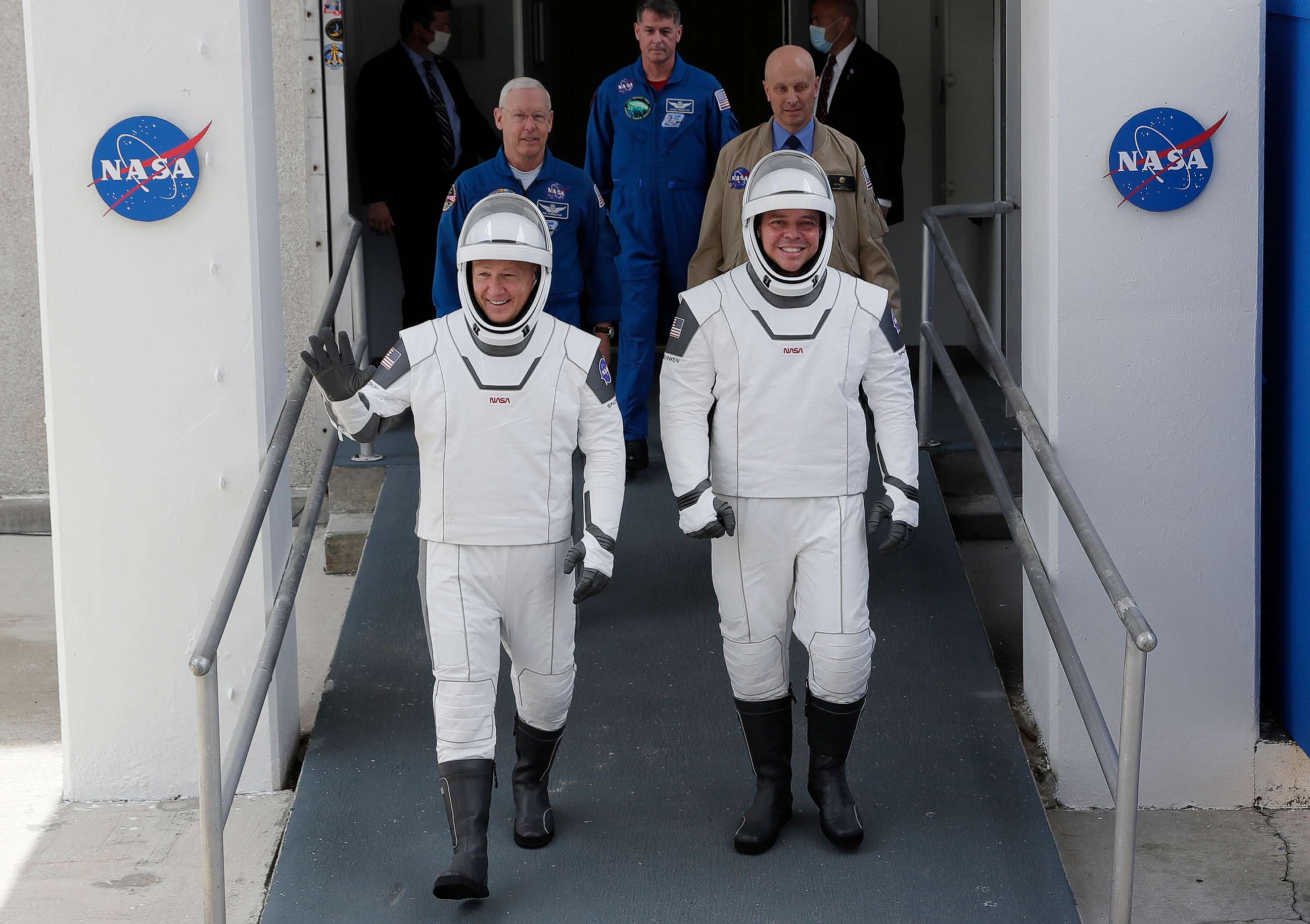 PHOTO: NASA astronauts Douglas Hurley, left, and Robert Behnken wave as they walk out of the Neil A. Armstrong Operations and Checkout Building on their way to Pad 39-A, at the Kennedy Space Center in Cape Canaveral, Fla., May 27, 2020.