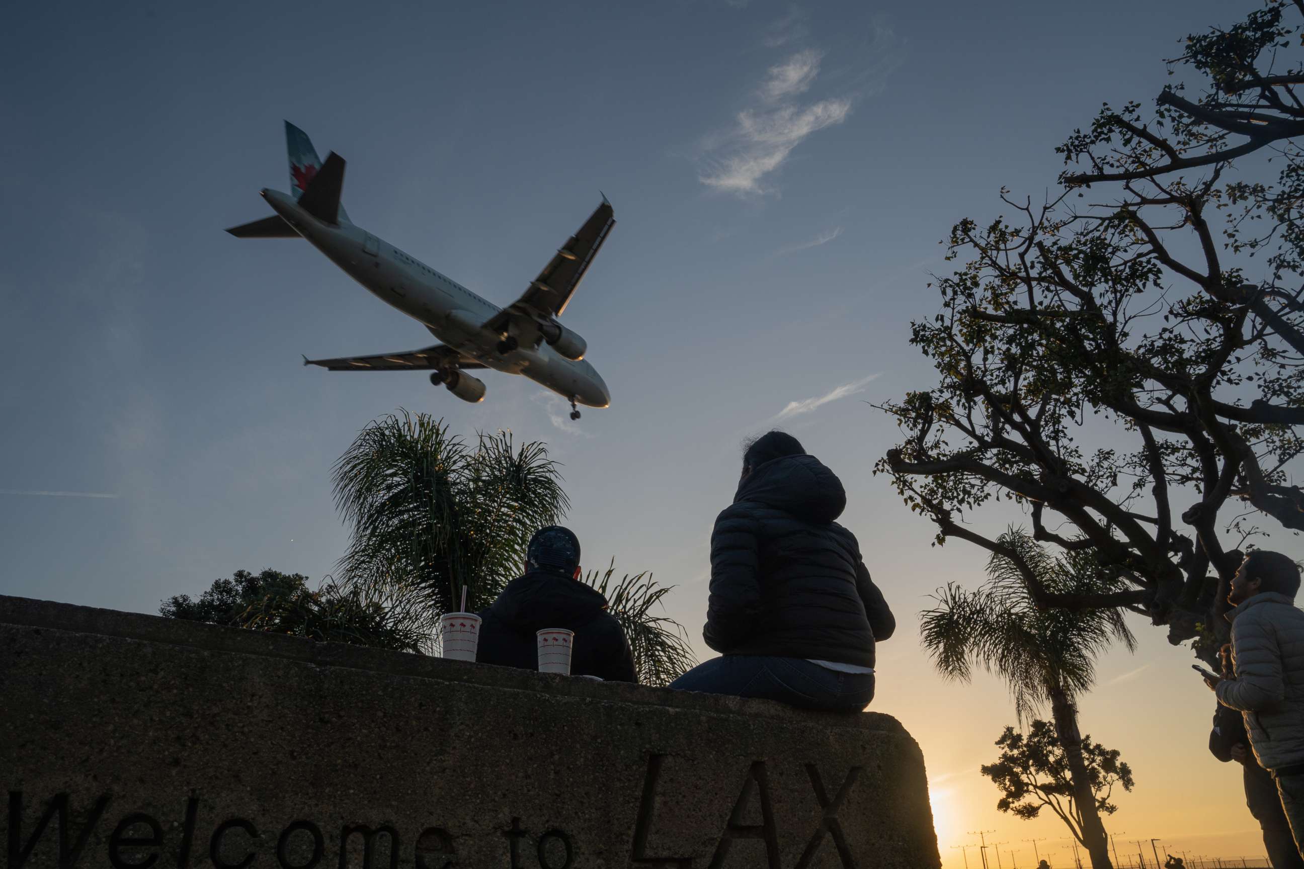 PHOTO: People watch an Air Canada Airbus SE A320 airplane land at Los Angeles International Airport (LAX) from a nearby park in Los Angeles, Nov. 23, 2020.