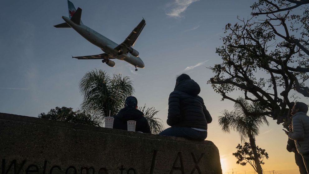 PHOTO: People watch an Air Canada Airbus SE A320 airplane land at Los Angeles International Airport (LAX) from a nearby park in Los Angeles, Nov. 23, 2020.