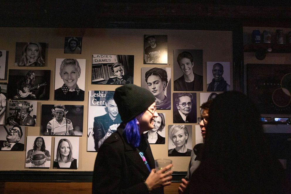 PHOTO: Bar patrons chat by a photo board of women at the Adams Morgan bar, A League of Her Own, in Washington, D.C. on Dec. 21, 2018.