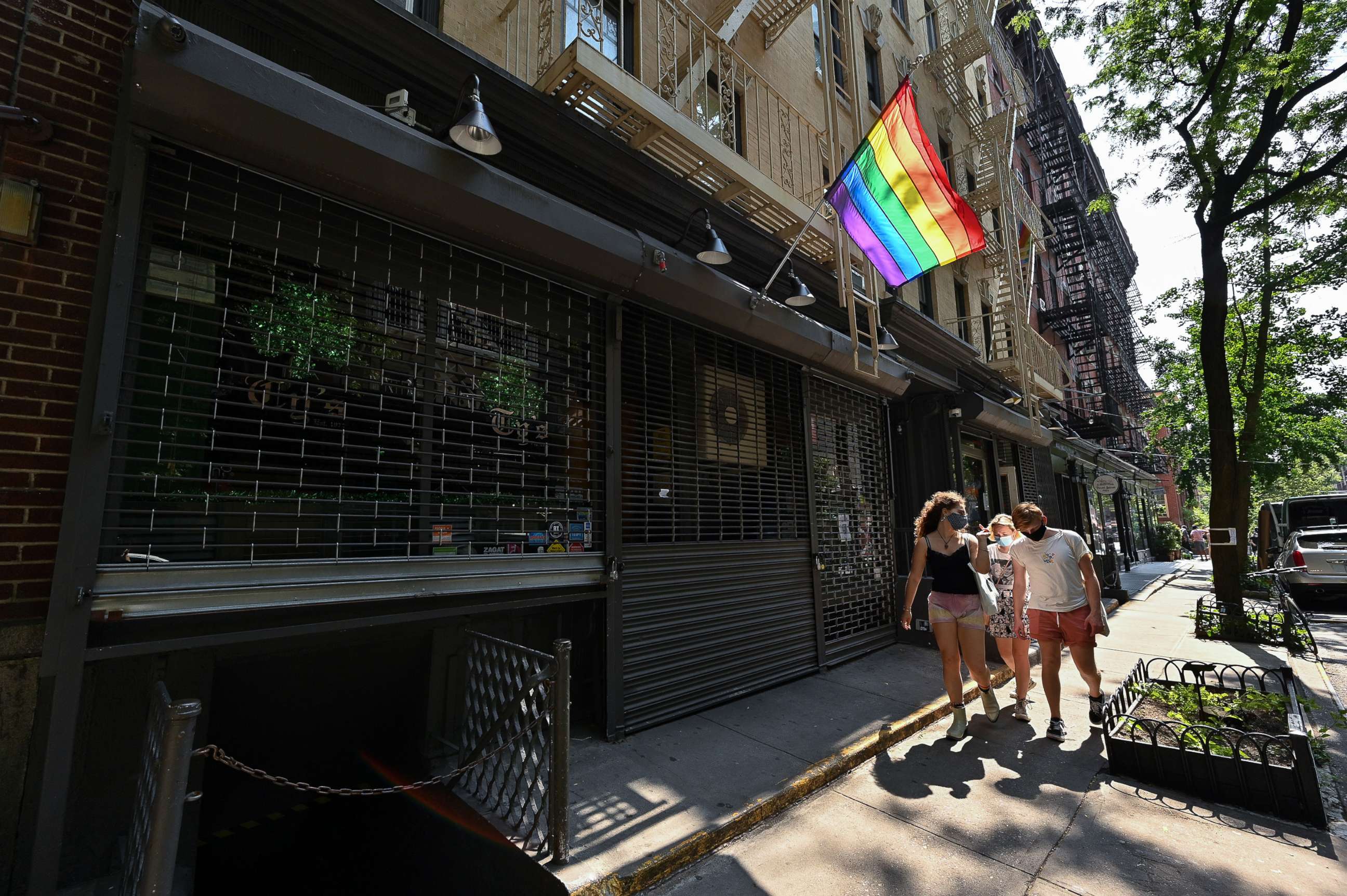 PHOTO: People walk past a temporarily closed Ty's Bar NYC on Christopher Street in the West Village, June 23, 2020, in New York.