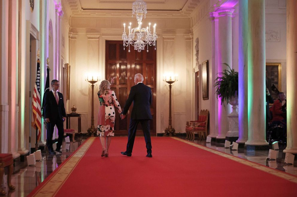 PHOTO:  President Joe Biden and first lady Jill Biden walk through the Cross Hall lit with rainbow colors following an event commemorating LGBTQ+ Pride Month in the East Room of the White House on June 25, 2021 in Washington, D.C.