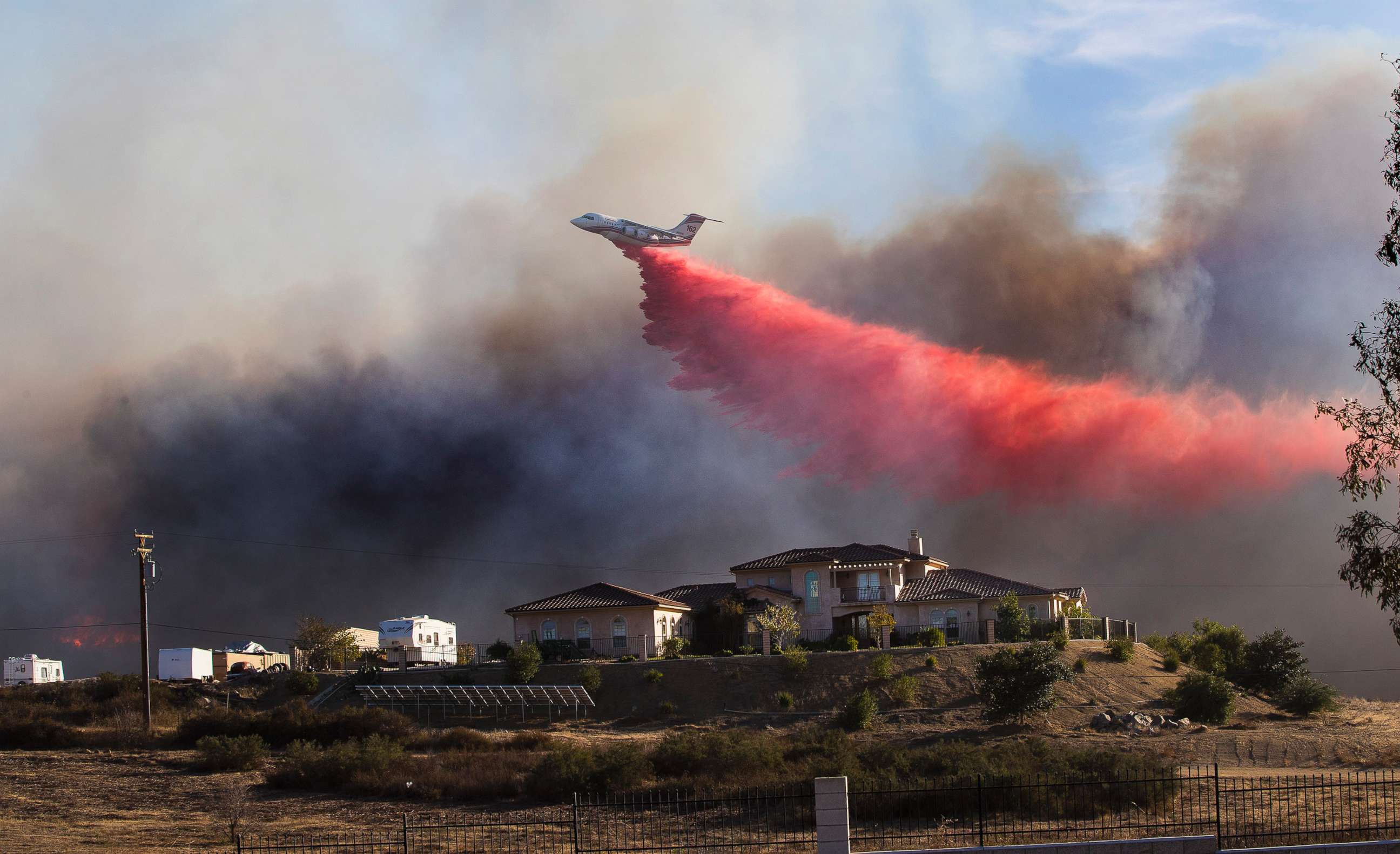 PHOTO: A plane drops fire retardant near a home to stop the wind driven Liberty Fire near Los Alamos Road on Dec. 7, 2017 in Murrieta, Calif.