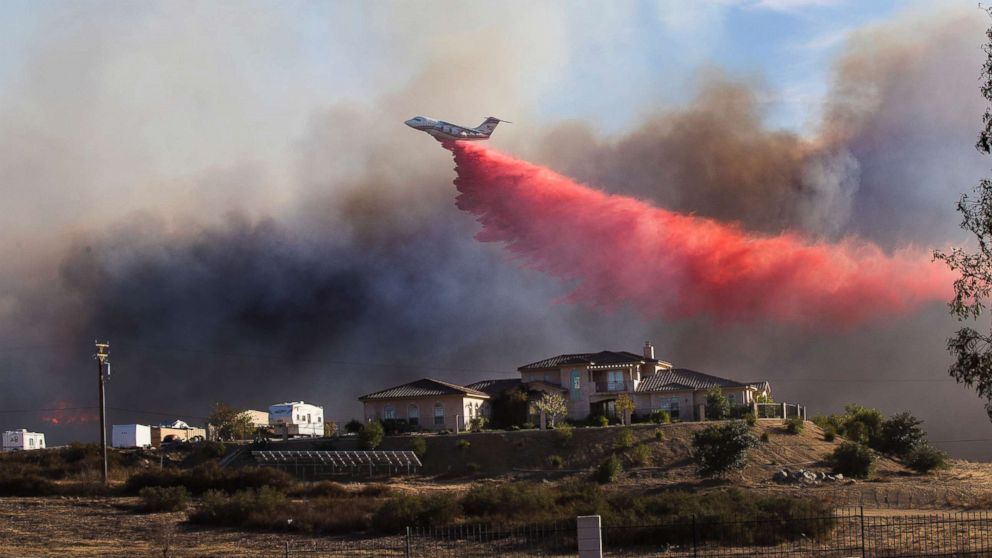 PHOTO: A plane drops fire retardant near a home to stop the wind driven Liberty Fire near Los Alamos Road on Dec. 7, 2017 in Murrieta, Calif.