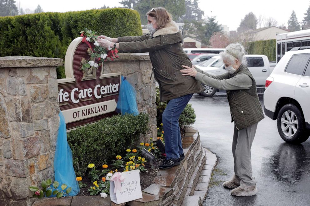PHOTO: Lori Spencer places a wreath on a sign at the Life Care Center of Kirkland upon leaving for her home with her mother, Judie Shape, 81, who had been diagnosed with coronavirus and was a resident at the center.