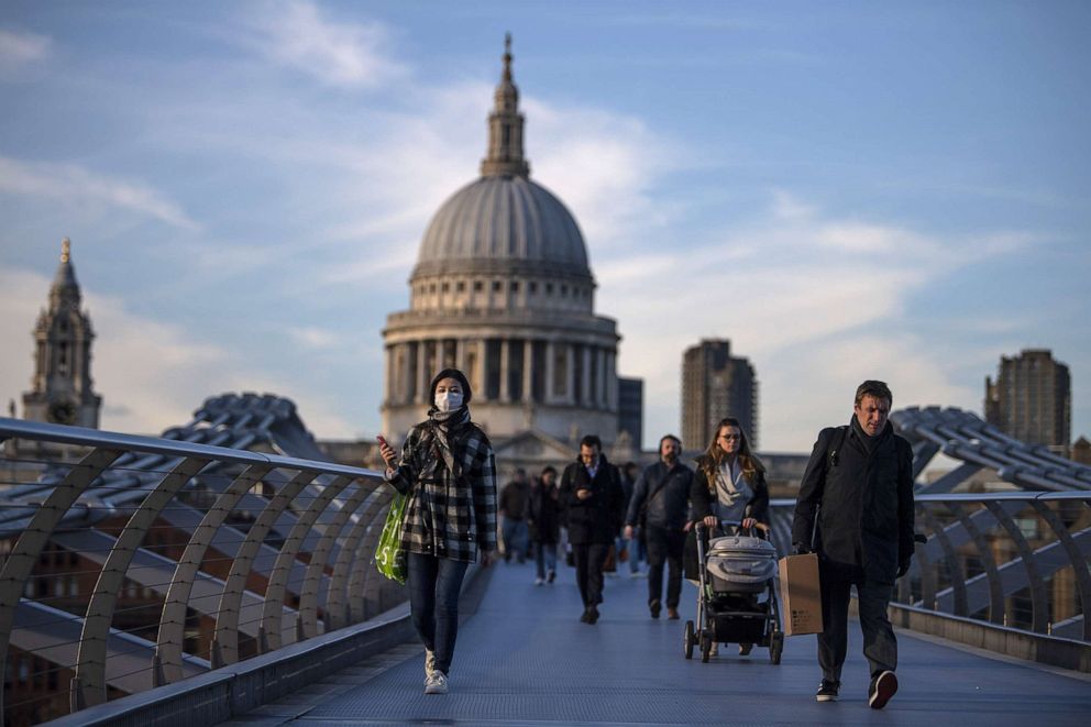 PHOTO: People cross the millennium bridge in front of St. Pauls Cathedral, March 16, 2020, in London, England.