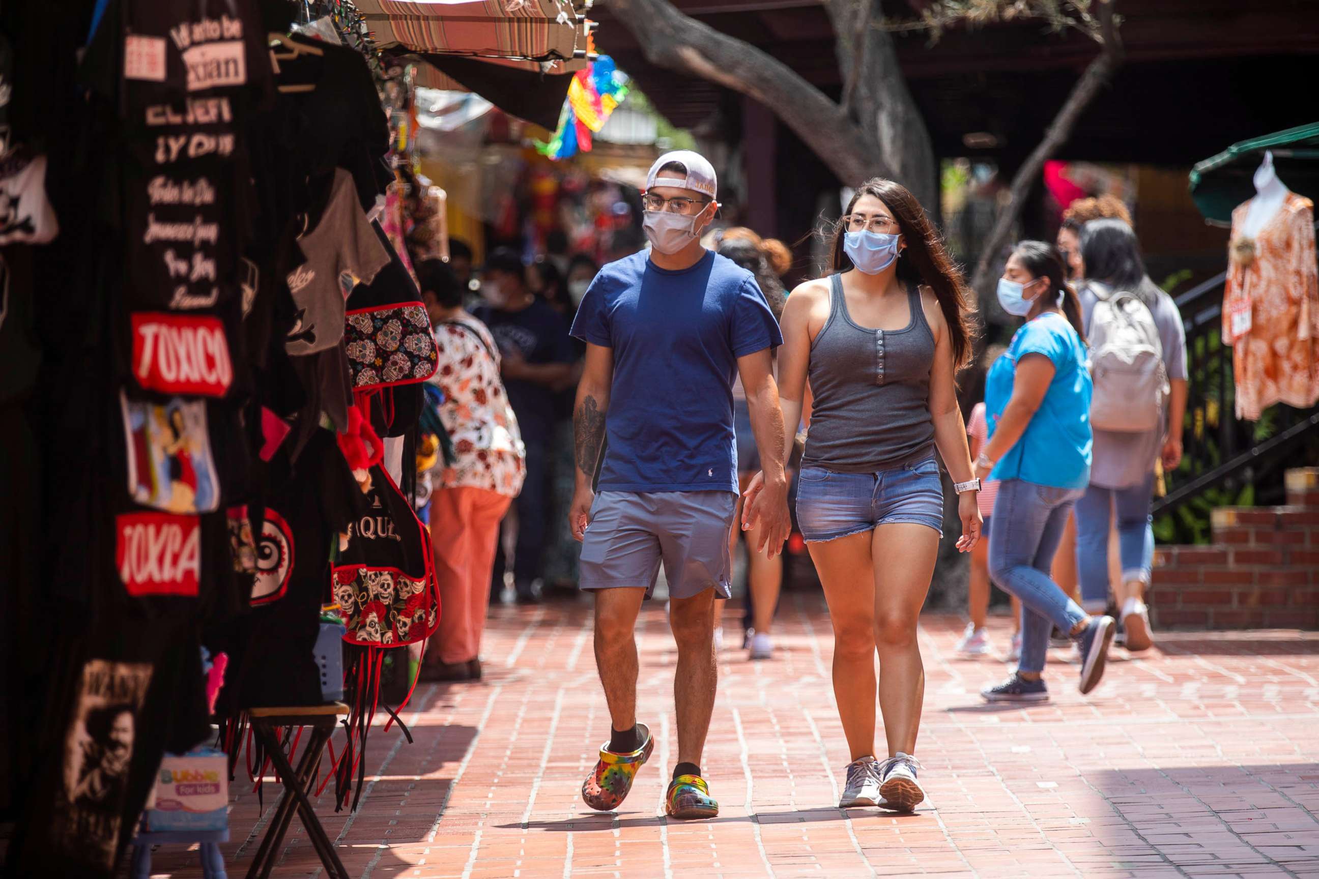 PHOTO: Pedestrians wearing Covid-19 masks walk through Olvera Street in Los Angeles, June 29, 2021.