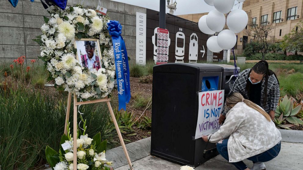PHOTO: Nursing student Samantha Mesa hangs a sign in downtown Los Angeles on Jan. 19, 2022, with registered nurse Terri Thompson, right, in support of Sandra Shells at a memorial set up to her at the bus stop where she was attacked.