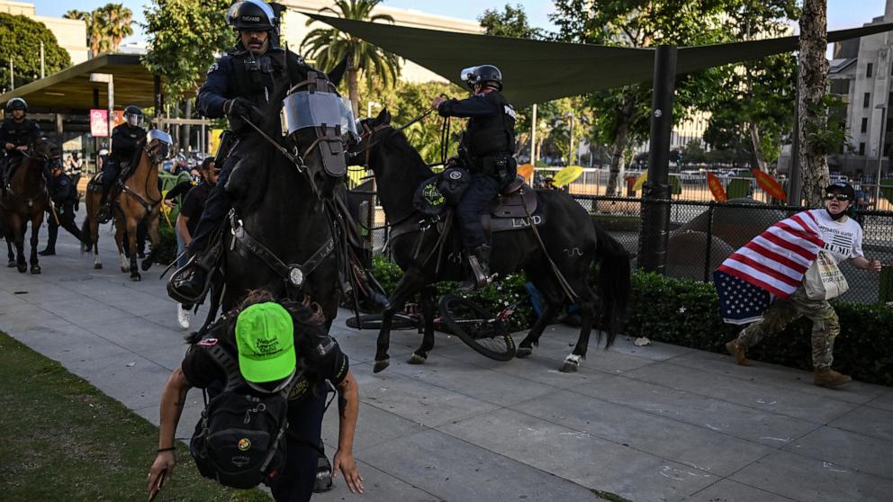 PHOTO: LAPD officers on horseback clash with protesters gathered near Los Angeles City Hall to protest against federal immigration operations on June 11, 2025.
