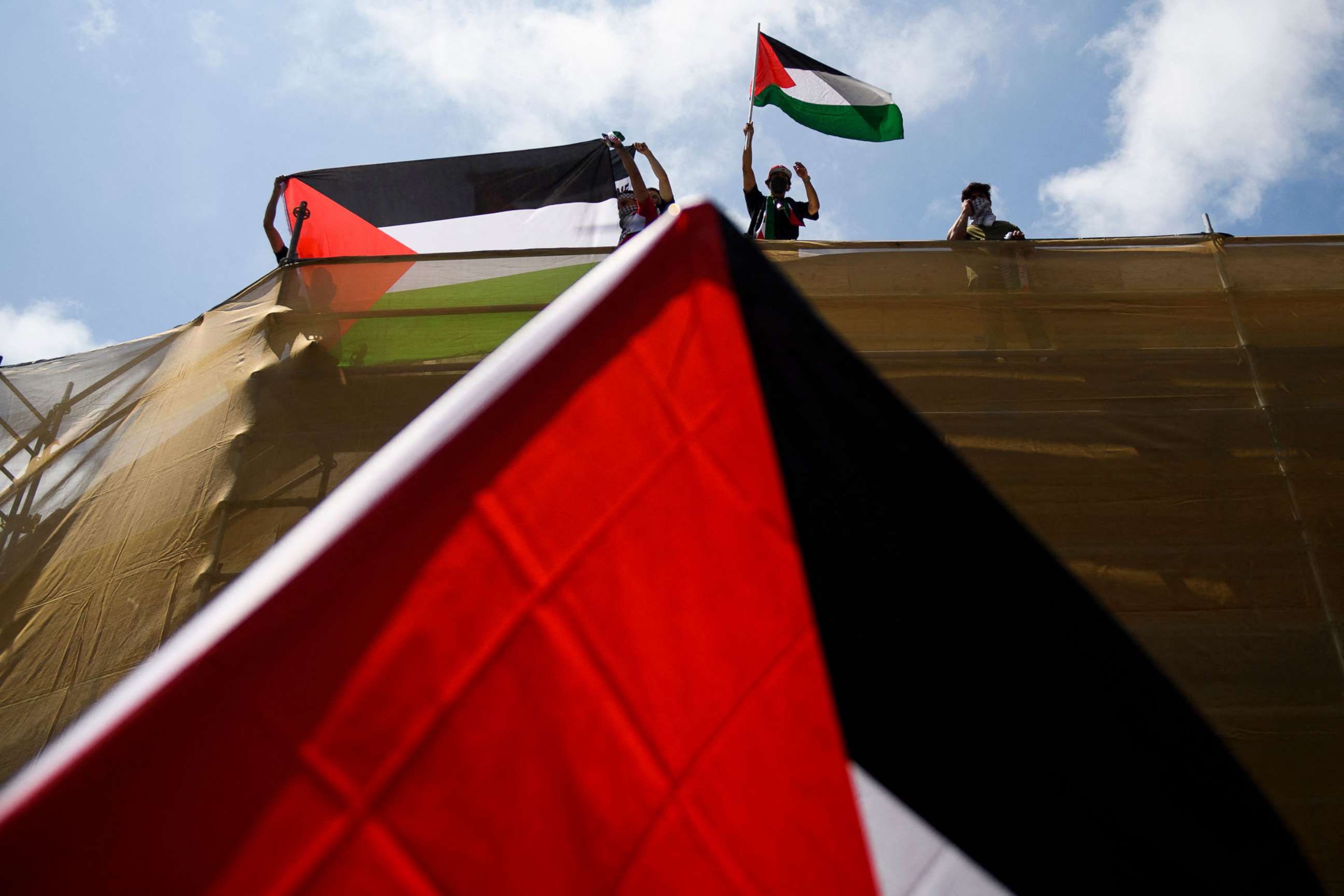 PHOTO: A demonstrator waves the flag of Palestine from the top of a building in support of Palestine during a rally in  the Los Angeles, May 15, 2021.