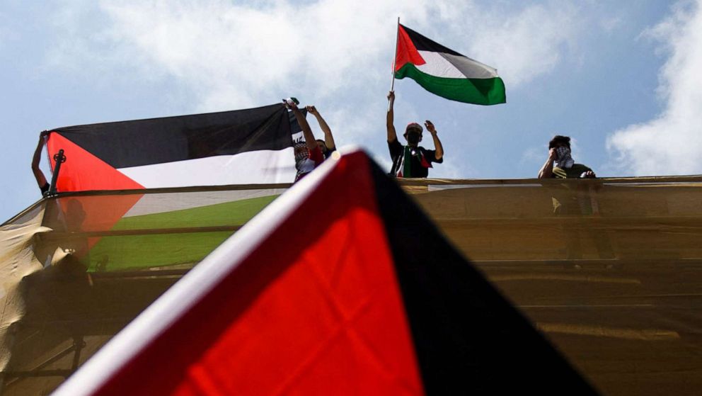 PHOTO: A demonstrator waves the flag of Palestine from the top of a building in support of Palestine during a rally in  the Los Angeles, May 15, 2021.