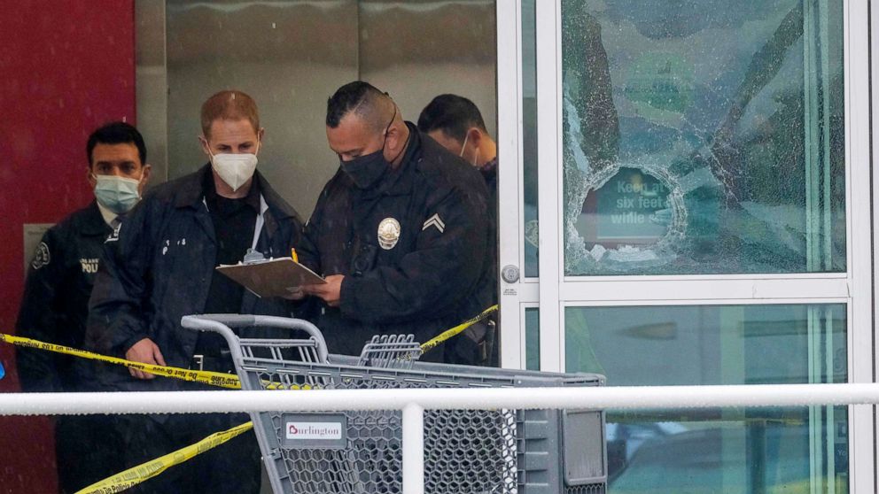 PHOTO: Police officers work near a broken glass door at the scene where two people were struck by gunfire in a shooting at the Burlington Coat Factory store in North Hollywood, Calif, Dec. 23, 2021. 