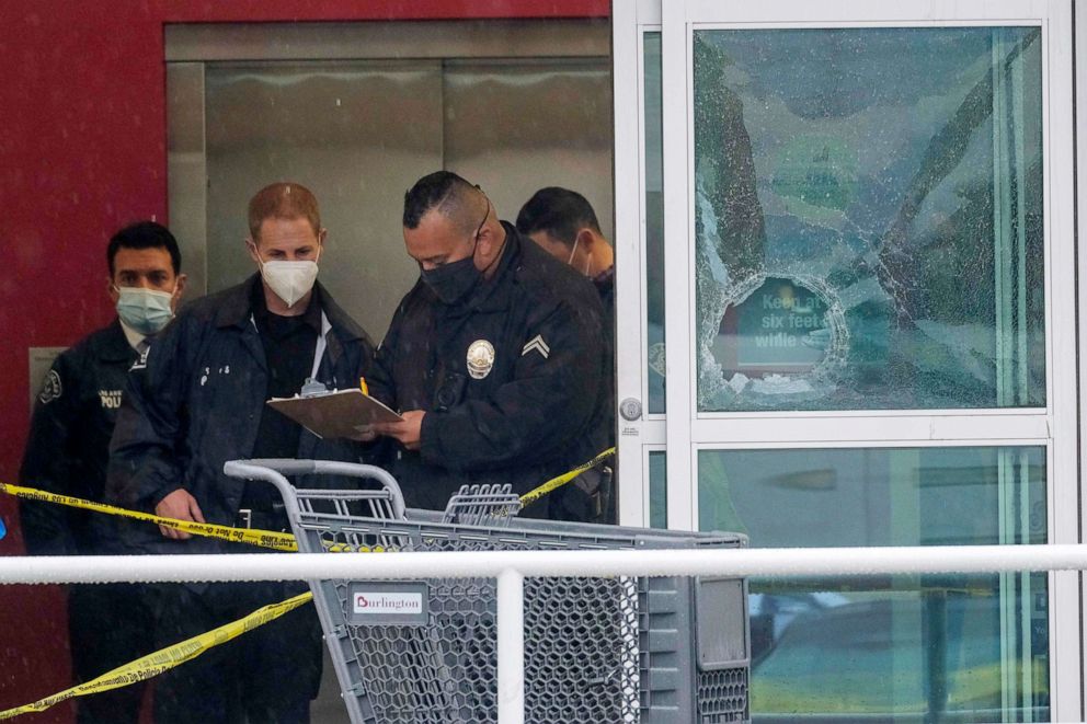 PHOTO: In this Dec. 23, 2021, file photo, police officers work near a broken glass door at the scene where two people were struck by gunfire in a shooting at the Burlington Coat Factory store in North Hollywood, Calif.
