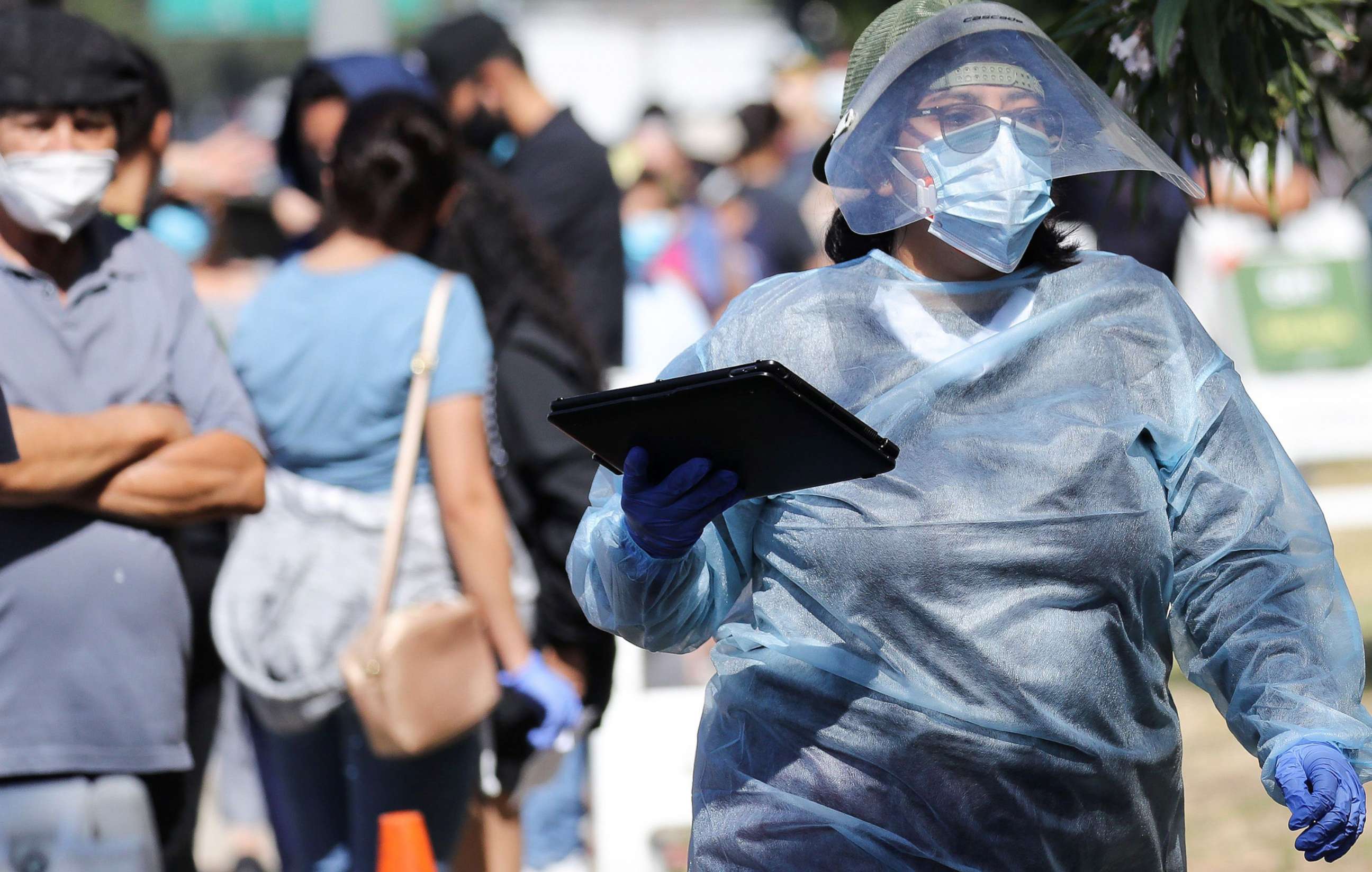 PHOTO: A worker in personal protective equipment (PPE) helps check in people at a COVID-19 testing center at Lincoln Park, July 7, 2020 in Los Angeles, during a spike in new coronavirus cases in California.