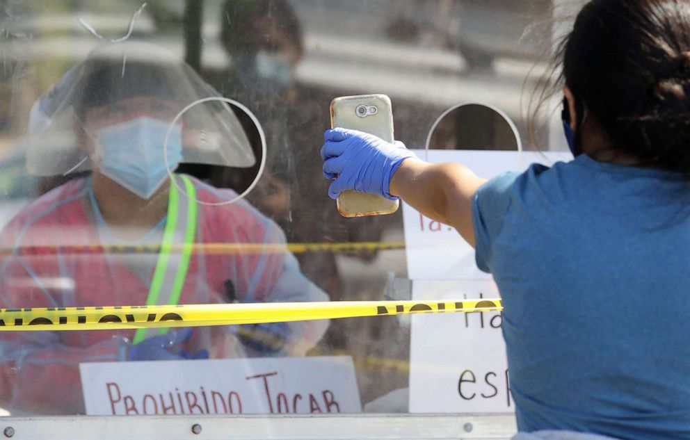 PHOTO: A woman displays information on her phone while checking in to be tested at a COVID-19 testing center, July 7, 2020 in Los Angeles, during a spike in new coronavirus cases in California.