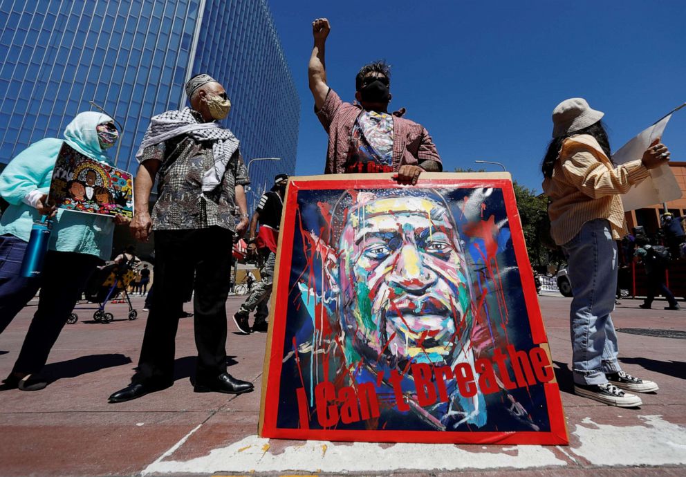 PHOTO: A man wearing a protective face mask raises his fist and holds a placard as he attends a protest against racial inequality in the aftermath of the death of George Floyd in Los Angeles, June 8, 2020.