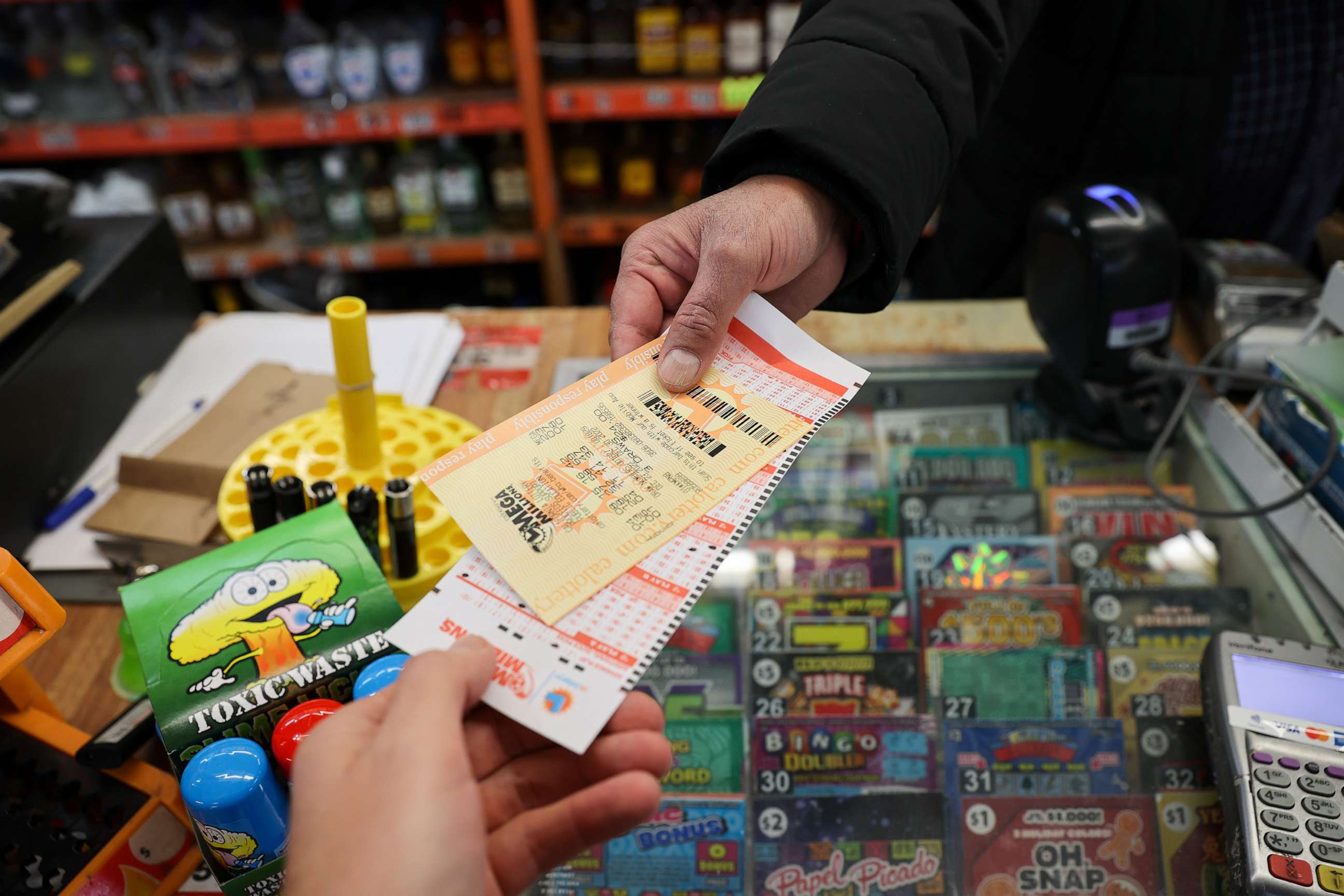 PHOTO: A cashier at a store hands a Mega Million lottery ticket to a person in Burlingame, Calif., Dec. 23, 2022.