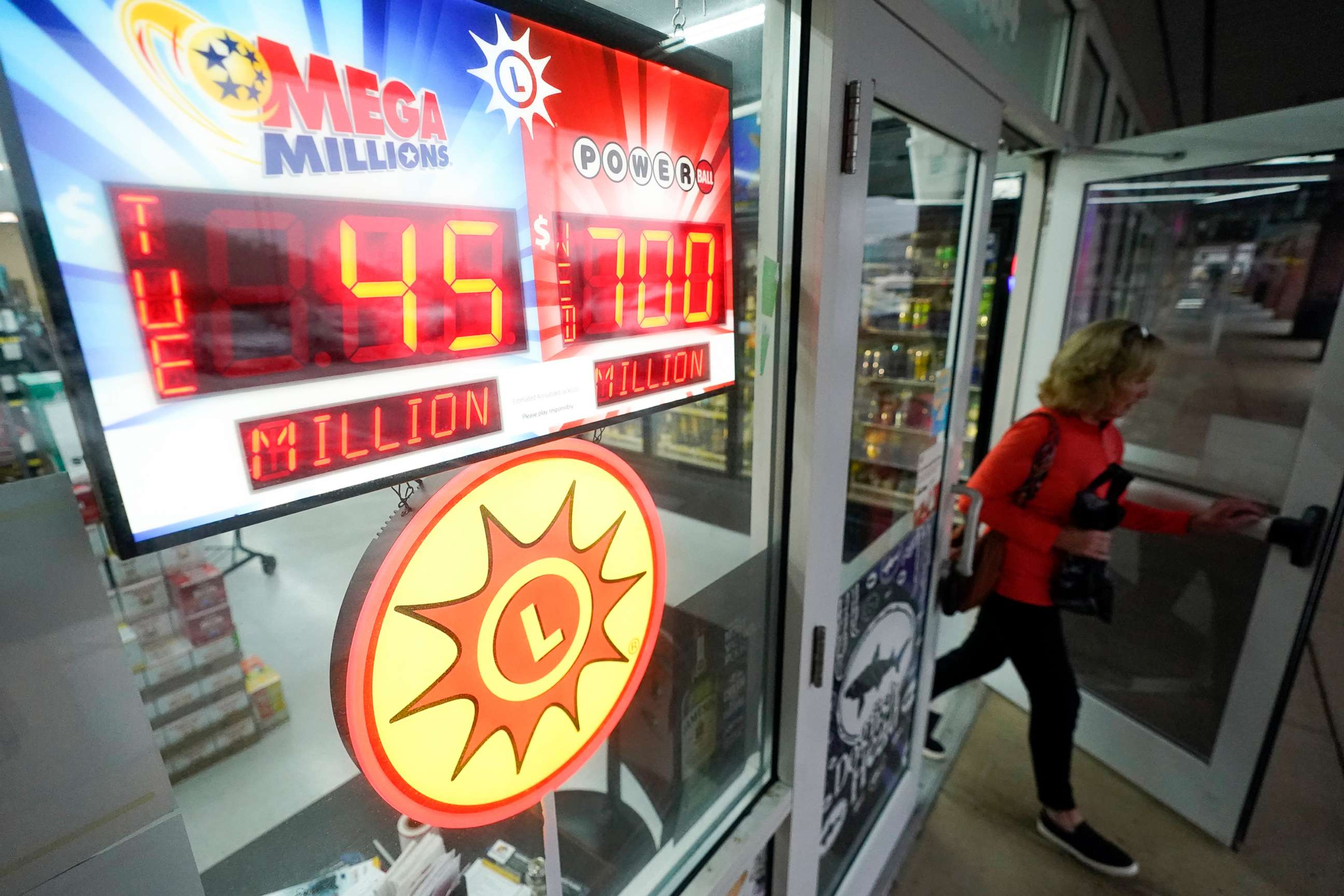 PHOTO: A patron leaves a liquor store as lottery jackpot signs are visible, Oct. 25, 2022, in Baltimore.