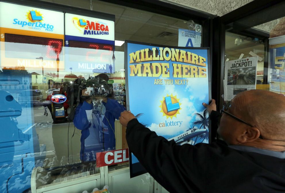 PHOTO: California Lottery Representative Terry White posts a  "Millionaire Made Here" lottery signs in the window of the Chino Hills 7-11 store where one of the winning Powerball tickets was sold, Jan. 14, 2015. 