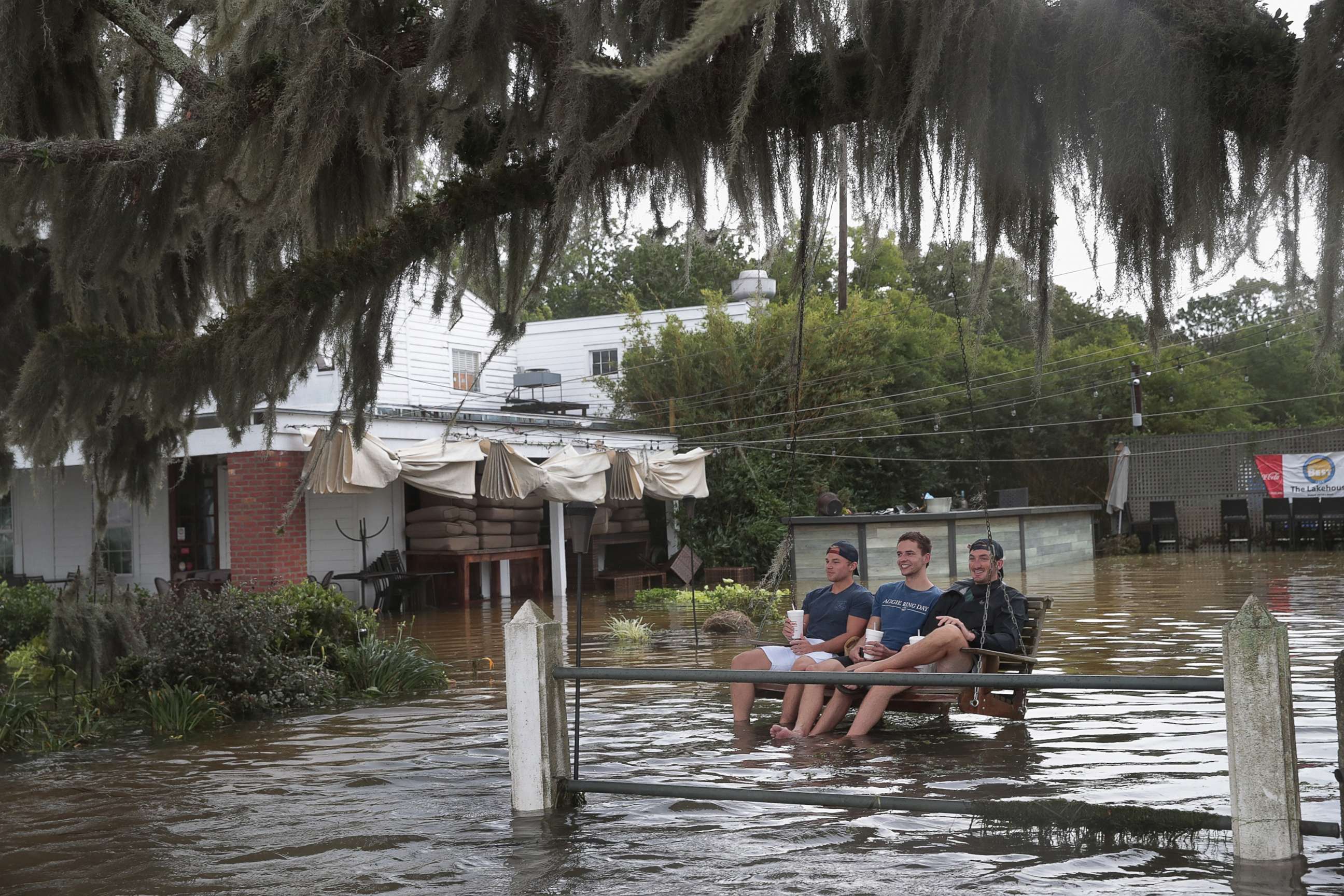 PHOTO: People sit in a swing surrounded by water from Lake Pontchartrain after the area flooded in the wake of Hurricane Barry on Saturday, July 13, 2019 in Mandeville, La. 
