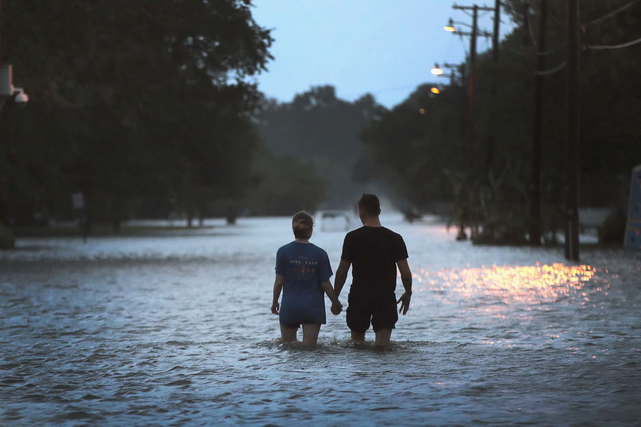 PHOTO: A couple strolls down Lakeshore Drive along the shore of Lake Pontchartrain after it was flooded in the wake of Hurricane Barry on Saturday, July 13, 2019 in Mandeville, La.