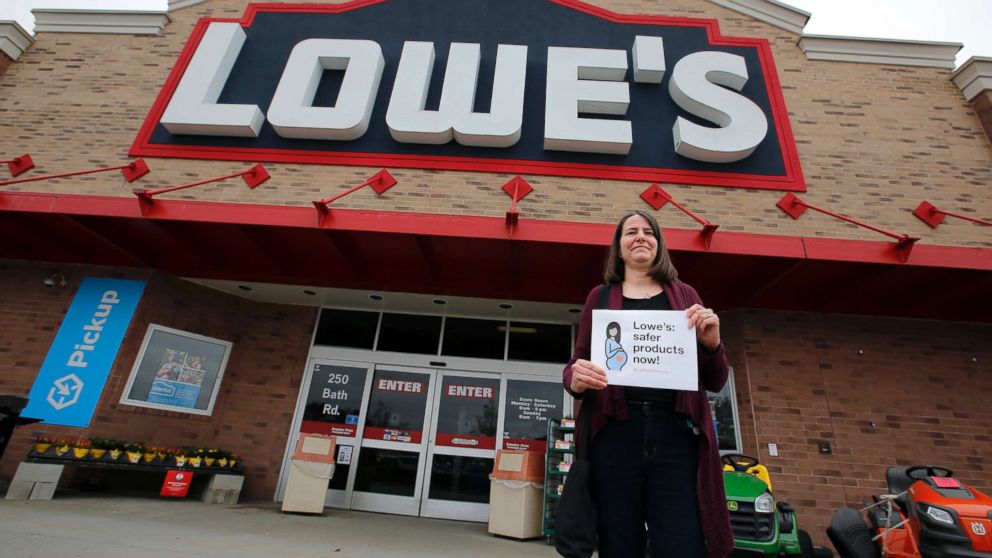 A woman holds a sign in front of a Lowe's store in Brunswick, Maine, while protests were held at several Maine locations in an effort to persuade Lowe's to discontinue the sale of paint strippers containing methylene chloride, May 10, 2018.