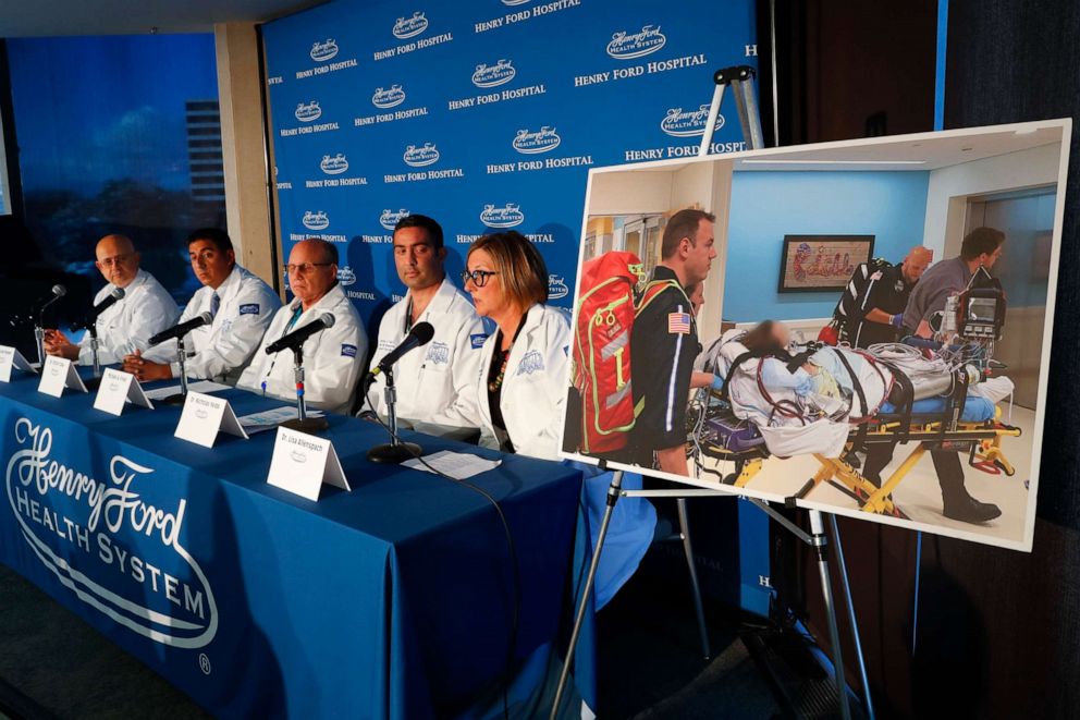 PHOTO: A photo of a patient being transported is displayed while medical staff at Henry Ford Hospital answer questions during a news conference in Detroit, Nov. 12, 2019.