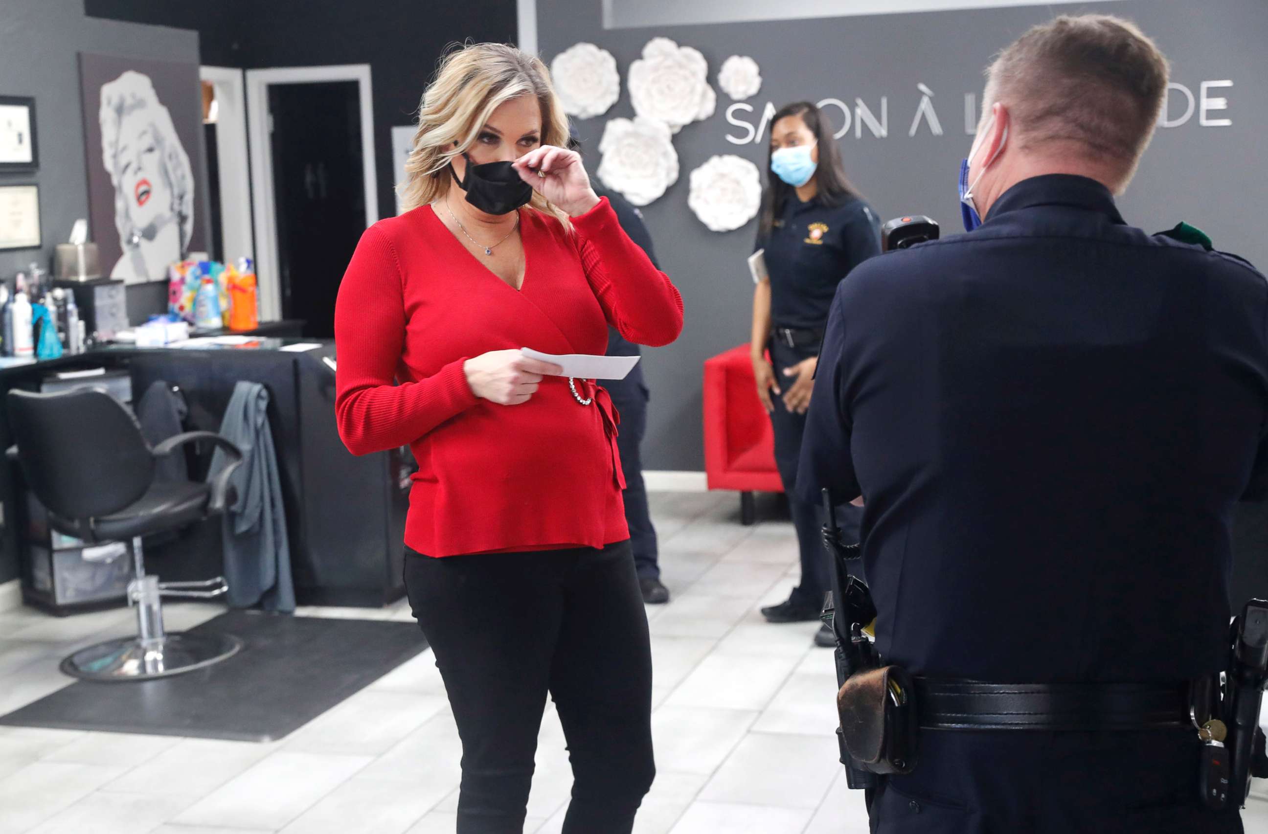 PHOTO: Salon owner Shelley Luther holds a citation and speaks with a Dallas police officer after she was cited for reopening her Salon A la Mode in Dallas, Texas, April 24, 2020. 