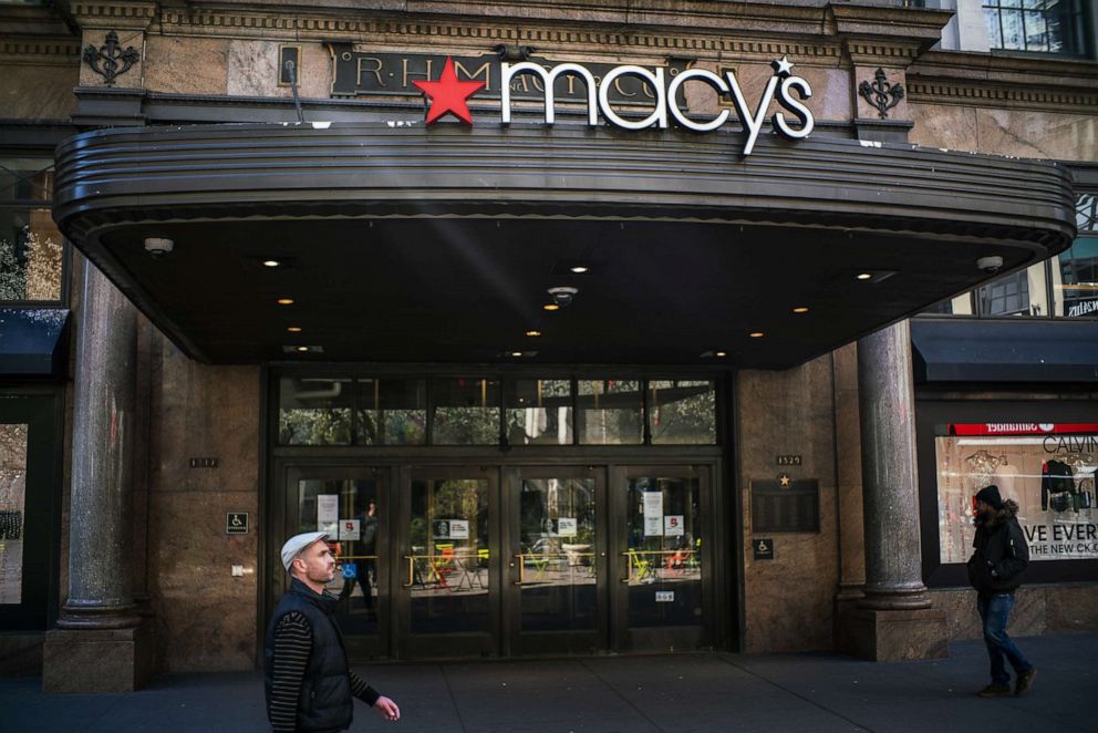 PHOTO: People walk by the Macy's store in New York that is closed due to the coronavirus on March 24, 2020.