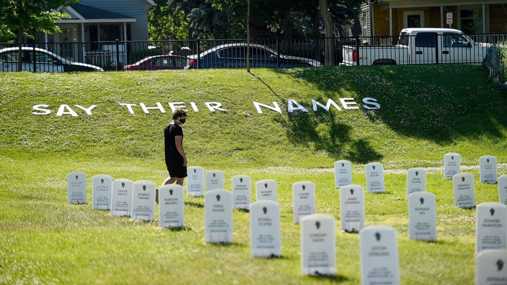 PHOTO: A man walks through a make shift cemetery near the intersection of 38th and Chicago in front of the Cup Foods, June 8, 2020.