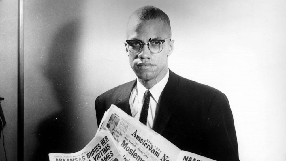 PHOTO: Portrait of human rights activist Malcolm X reading stories about himself in a pile of newspapers, circa 1963. (Photo by Three Lions/Hulton Archive/Getty Images)