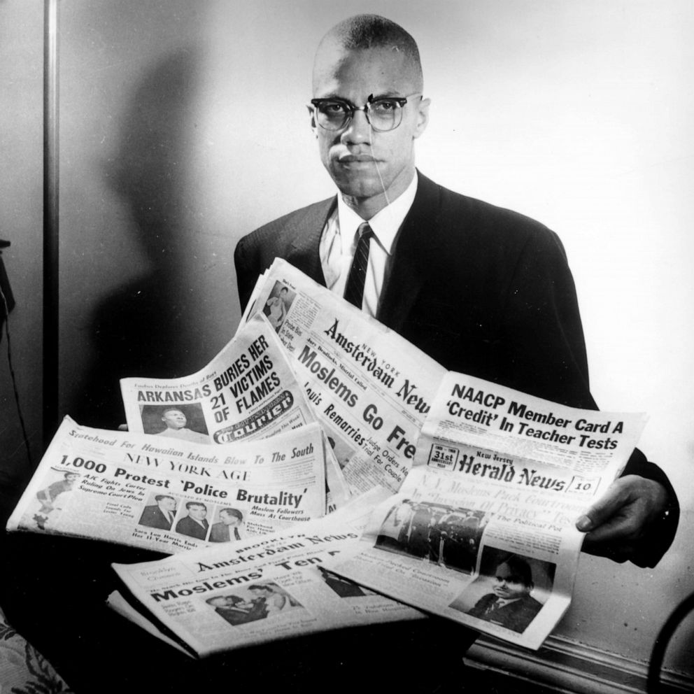 PHOTO: Portrait of human rights activist Malcolm X reading stories about himself in a pile of newspapers, circa 1963. (Photo by Three Lions/Hulton Archive/Getty Images)