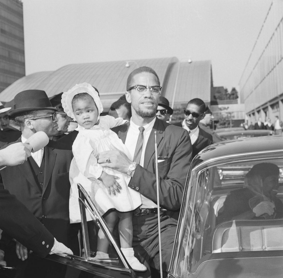 PHOTO: In this May 21, 1964, file photo, Malcolm X carries his daughter, Ilyasah, as he enters car at John F. Kennedy International Airport in New York.