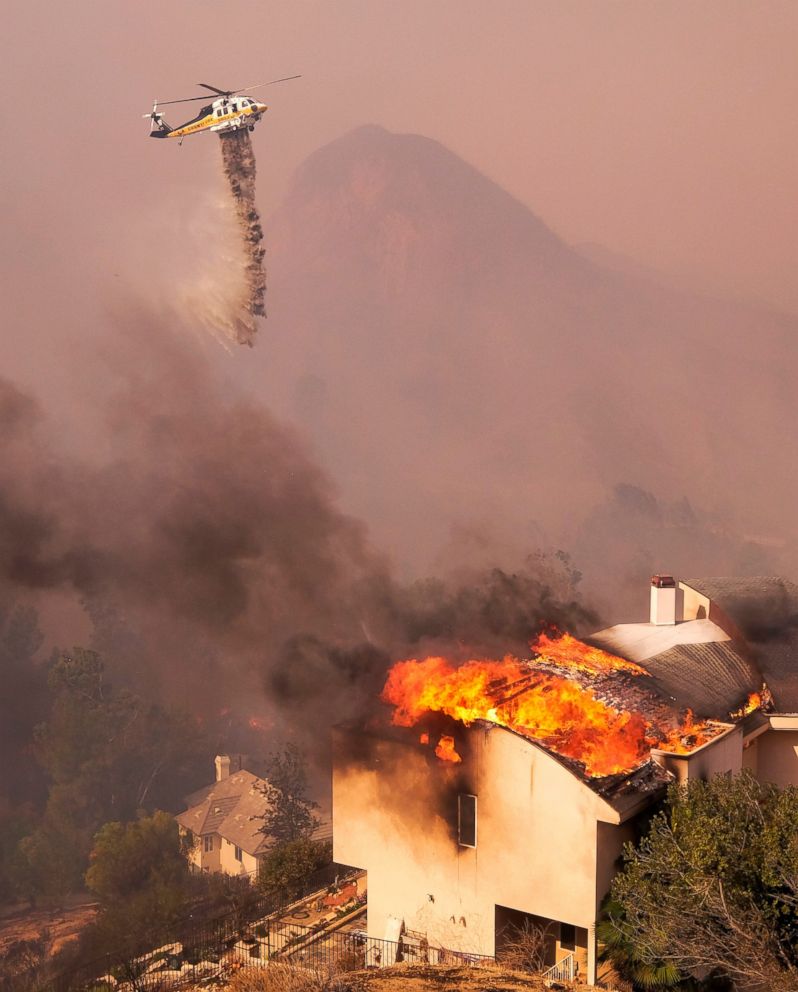 PHOTO: A helicopter drops water while a wildfire burns a home near Malibu Lake in Malibu, Calif., Friday, Nov. 9, 2018.