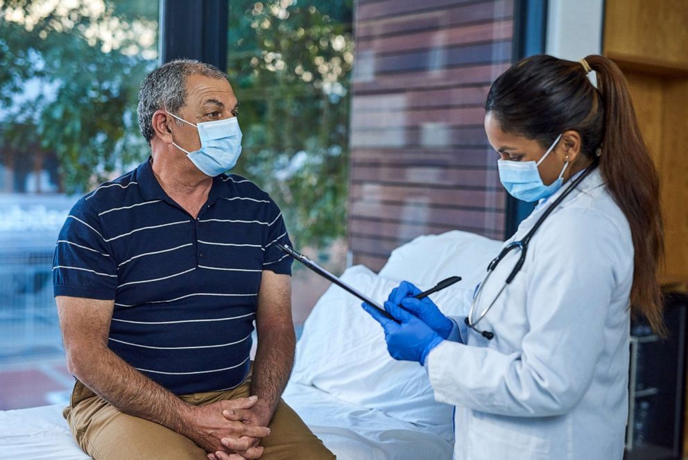 PHOTO: Shot of a doctor writing notes during a consultation with a senior patient