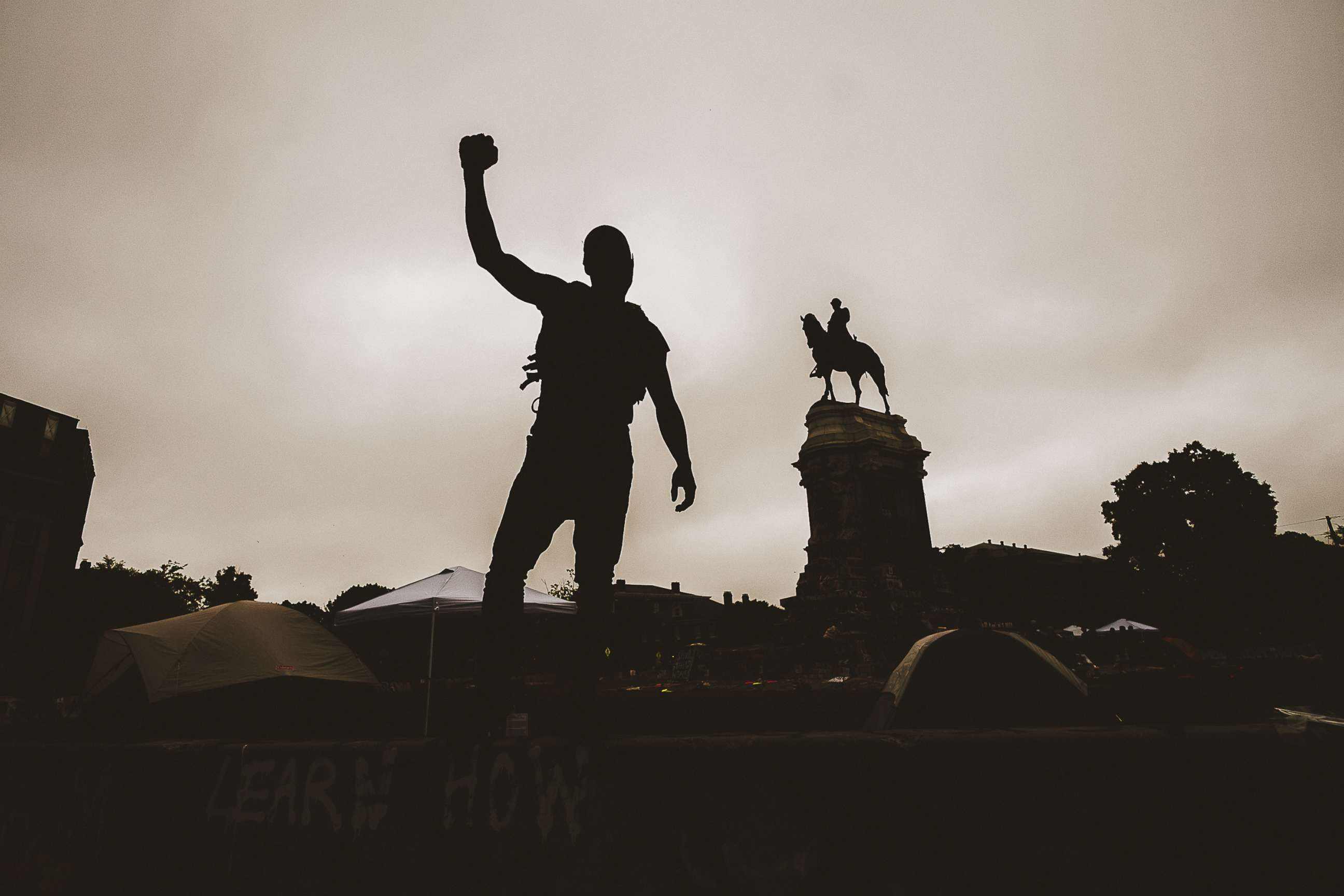 PHOTO: This photo taken on June 20, 2020, shows a silhouette of a man with his fist in the air at the Robert E. Lee monument in Richmond, Virginia. Protesters for racial justice have called for statues of Confederate leaders, like Lee, to be taken down.