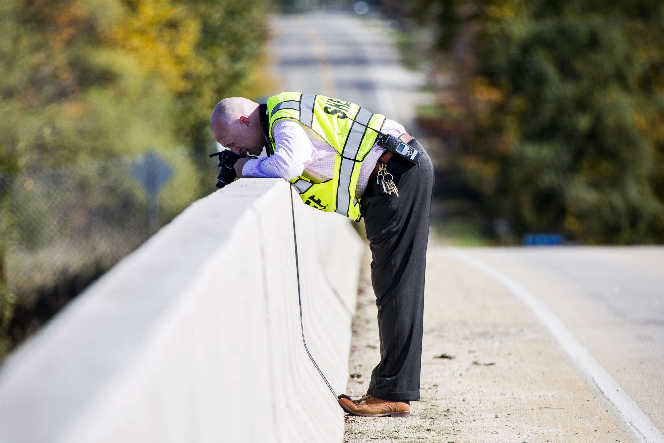 Genesee County Sheriff's Office investigator takes photos from an overpass on Oct. 20, 2017, in Vienna Township, Mich. where a rock was thrown from, smashing a car windshield and killing a 32-year-old man on Oct. 18. 